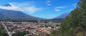 Watermaker needs in Guatemala. Aerial view of the city in Guatemala with the mountains in the back. The sky is blue with white clouds.